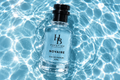 H & B PRESTIGE NOVAIRE eau de parfum bottle resting in clear rippling water with sunlight reflections